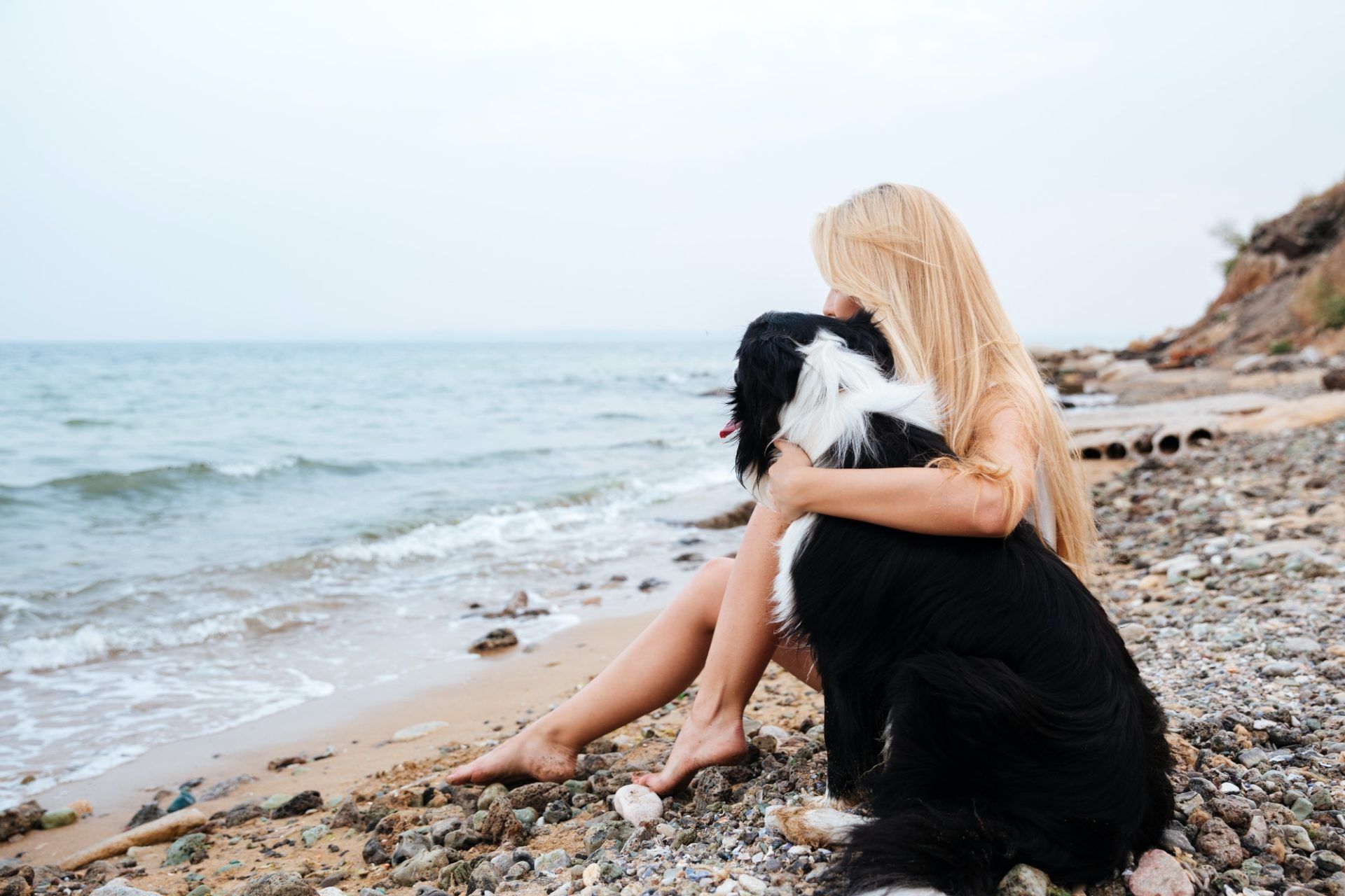woman-sitting-and-hugging-a-dog-on-the-beach